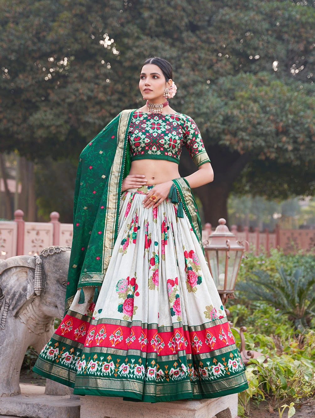 Woman in traditional outfit with floral design in a garden setting